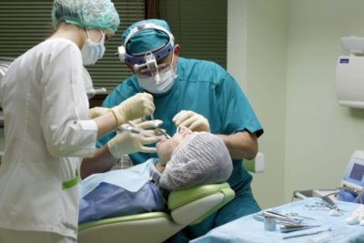 Хирург-стоматолог выполняет имплантацию